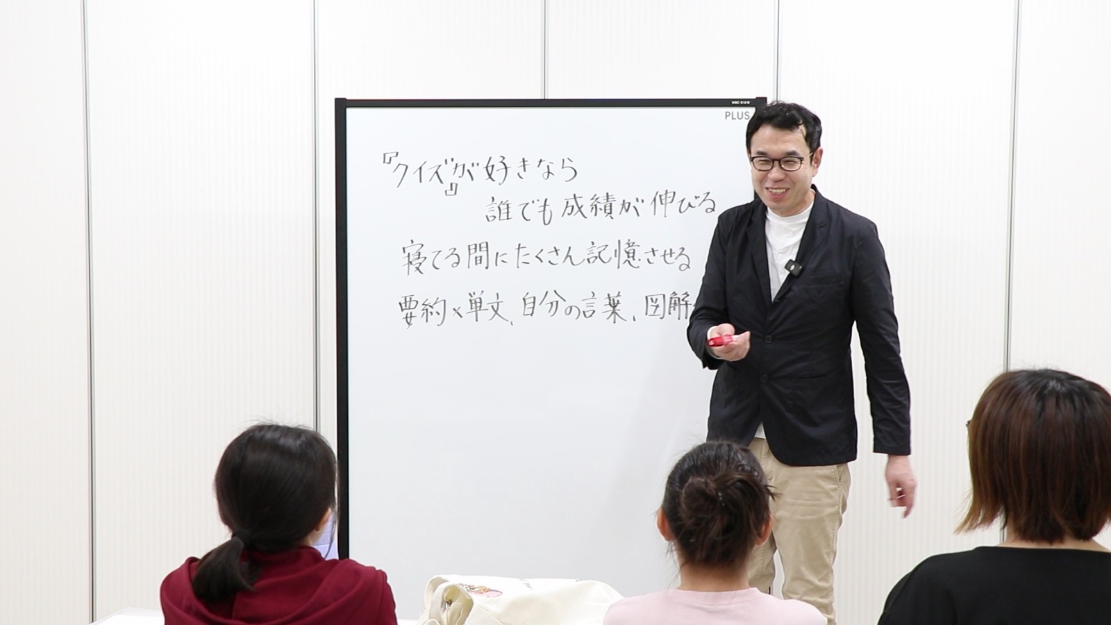 親子ゼミで、ホワイトボードに「クイズが好きなら誰でも成績が伸びる」と書いて話す塾長の中込宏樹